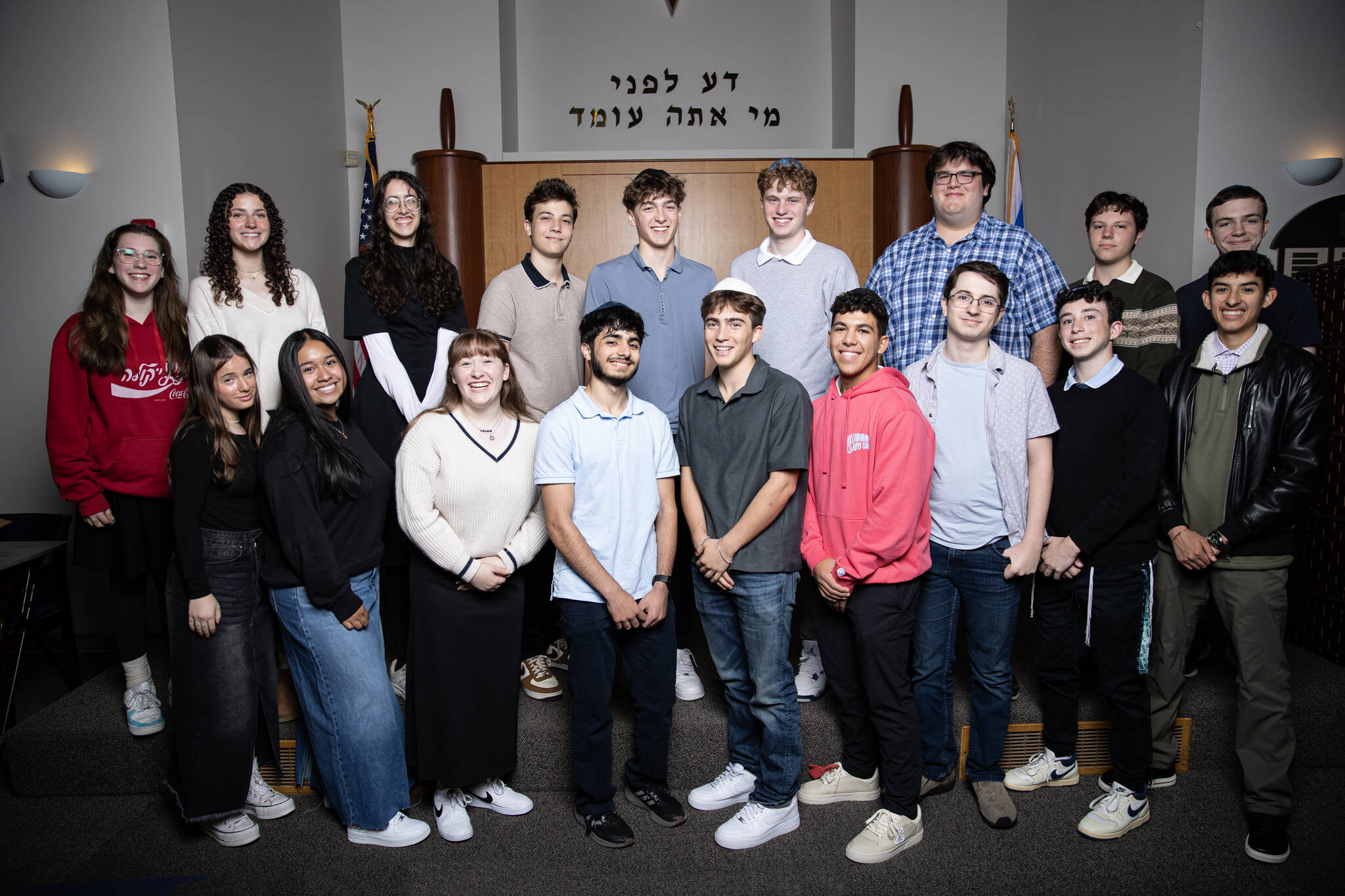 Northwest Yeshiva High Schools Class of 2025 graduation ceremony took place on June 5 at Sephardic Bikur Holim Congregation in Seward Park. Eighteen of the 19 graduates are pictured. They are: Front row left to right: Elianna Rothstein, Leah Gonzalez, Ariana Balkany, Eli Khaimov, Rubin Owen, Sol Levy, Didi Desmond, Izzy Hoffman and Emmanuel Spinoza; back row left to right: Celia Rosenbaum, Paulina Gamel, Evelyn Edwards, Isaac Almo, Ben Weichbrodt, Joe Benoliel, Noam Rosenfeld, Zach Saltsman and Jacob Klinghoffer. Not pictured: Amiel Robicsek. Photo courtesy of Mason Kelley