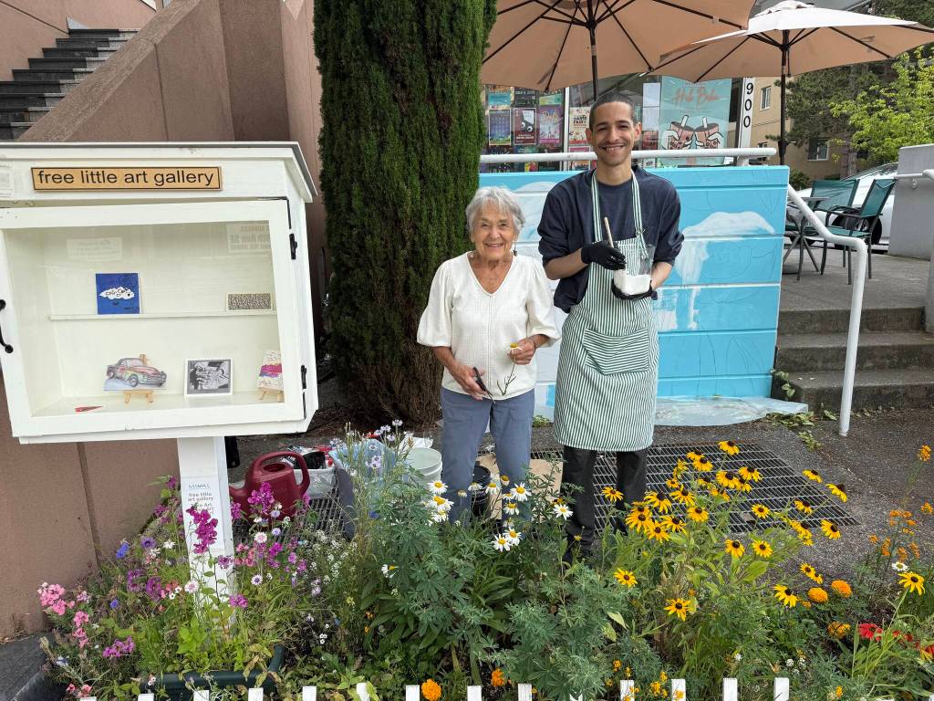 Mercer Island Visual Arts League artist/gardener June Lindsey and muralist Daniel Menezes showing off the flower garden, Free Little Art Gallery and mural in process. Photo courtesy of the Mercer Island Visual Arts League