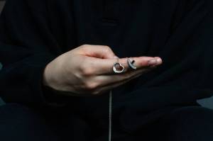 A former student at Mercer Island High School poses for an anonymous portrait while holding two Tiffany necklaces outside her apartment on Oct 13, 2025. The former student, who graduated in 2011, says that former English teacher Curtis Johnston pursued an inappropriate sexual relationship with her during her senior year of high school, which extended through her freshman year of college. When she left for college, Johnston gifted her the necklaces. (Moe K. Clark/InvestigateWest)
