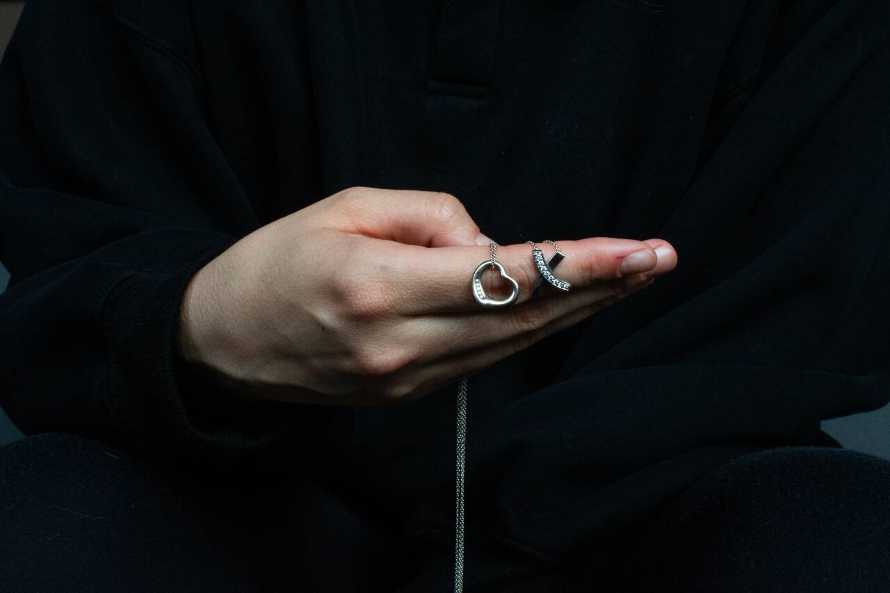 A former student at Mercer Island High School poses for an anonymous portrait while holding two Tiffany necklaces outside her apartment on Oct 13, 2025. The former student, who graduated in 2011, says that former English teacher Curtis Johnston pursued an inappropriate sexual relationship with her during her senior year of high school, which extended through her freshman year of college. When she left for college, Johnston gifted her the necklaces. (Moe K. Clark/InvestigateWest)