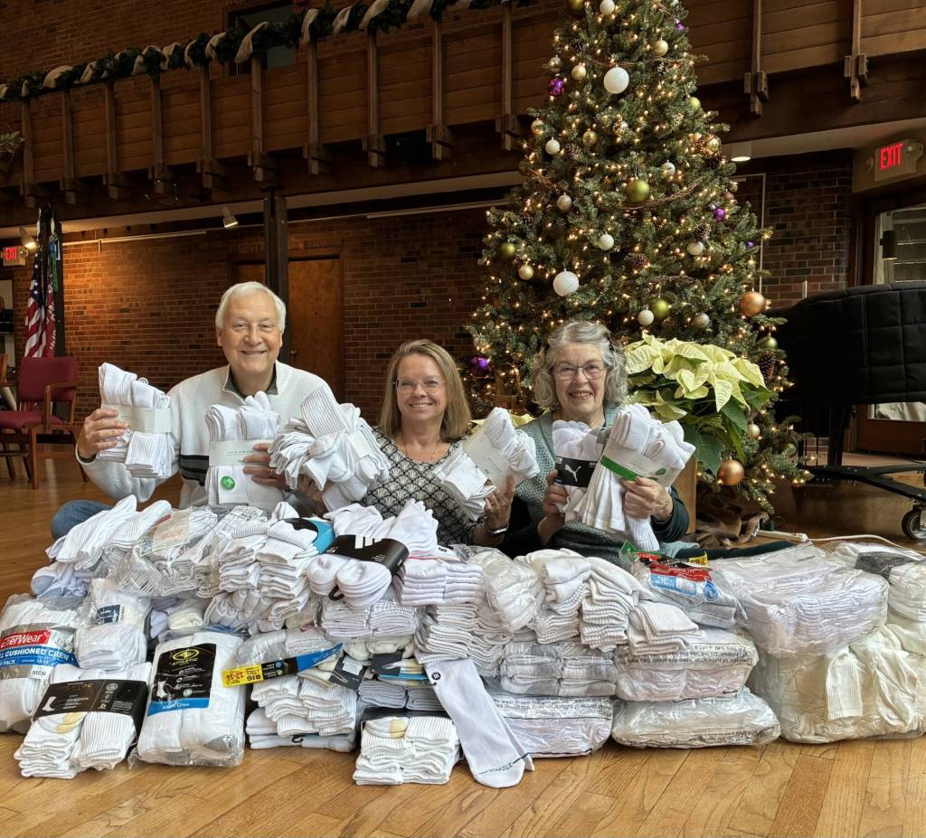 From left to right at Congregational Church on Mercer Island, Terry Pepple, Pastor Rev. Jennifer Castle and Diane Calvert gather with 800 pairs of the 8,000-plus pairs of socks the church will donate to Operation Nightwatch this year. Courtesy photo