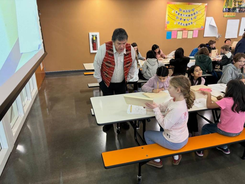 Storyteller, educator and artist Roger Fernandes of the Lower Elwha SKlallum tribe recently visited Northwood Elementary School third-graders who gathered as a group in the schools commons to learn how Native Americans created paint from charcoal. Students then painted a salmon they had traced earlier on a plank of wood. Fernandes is visiting third-graders in all four elementary schools this year through grants from the Mercer Island Schools Foundation. Photo courtesy of the Mercer Island School District