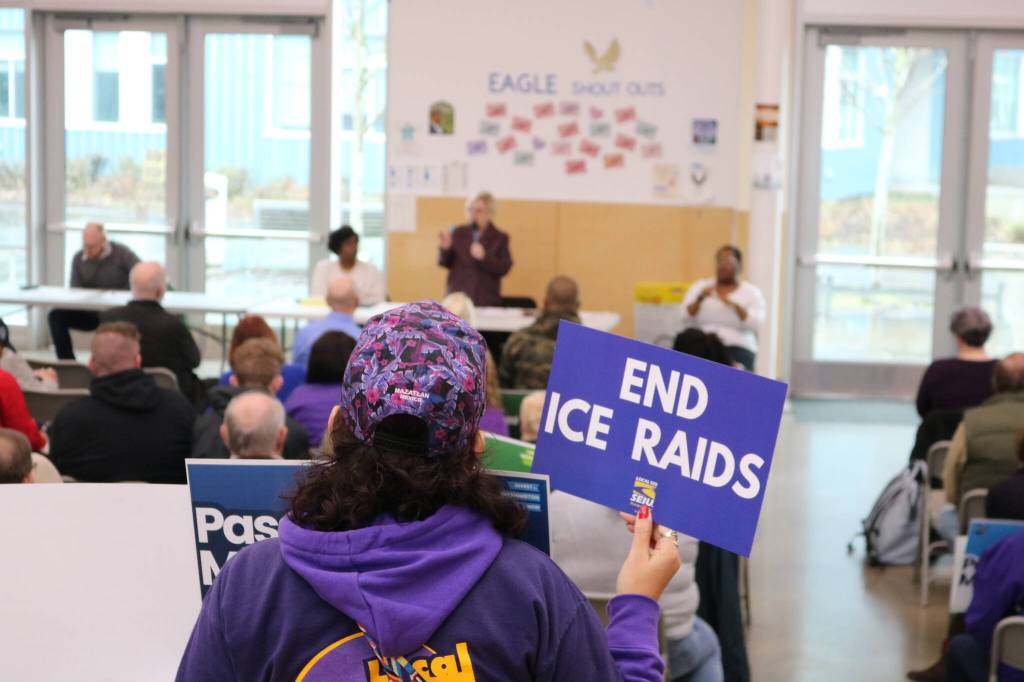 An attendee at the Feb. 21 town hall in Federal Way holds a sign calling for an end to ICE raids. Courtesy photo