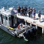 A group recites the pledge of allegiance during a Mercer Island Police Department Marine Patrol American flag retirement and replacement ceremony on the dock of the Virginia Mason Athletic Center. Mercer Island Police Department drone photo